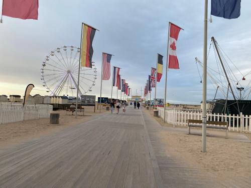 une promenade avec des drapeaux et une grande roue sur la plage dans l'établissement Charmant studio à Ouistreham, à Ouistreham