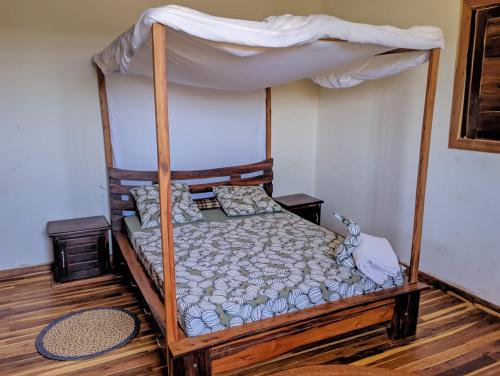 a bedroom with a wooden bed with a canopy at La maison d'hôte de la Forêt Retrouvée in Mahajanga