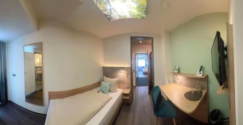Dormitorio pequeño con cama y espejo en IN VIA Hotel, en Paderborn