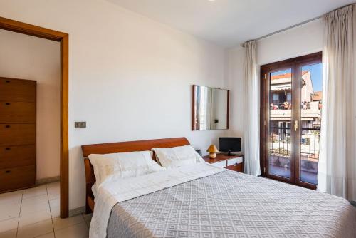 a white bedroom with a bed and a window at Capomulini House by Wonderful Italy in Acireale