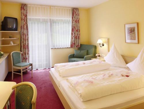 una stanza d'albergo con due letti e una sedia di Dornröschen a Höchst im Odenwald