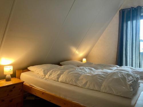 a bed in a room with two lamps next to a window at De Druif 6 pers holiday home close to the National Park Lauwersmeer in Anjum