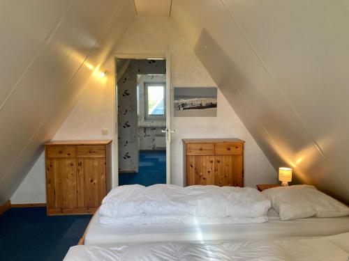 1 dormitorio con cama blanca y armarios de madera en De Druif 6 pers holiday home close to the National Park Lauwersmeer, en Anjum