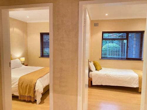 1 dormitorio con 2 camas y ventana en A Home in Timour Hall, en Ciudad del Cabo