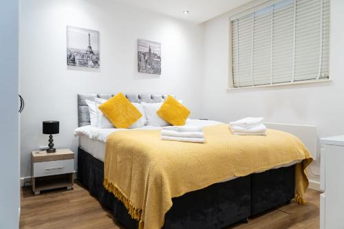a bedroom with a large bed with yellow pillows at Smart Central Woking 1 Bedroom Apartment in Woking