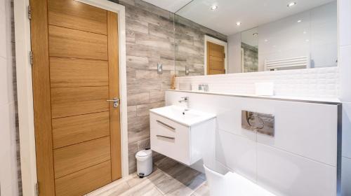 a bathroom with a white sink and a mirror at Smart Central Woking 1 Bedroom Apartment in Woking