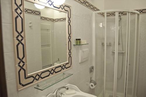 a bathroom with a mirror and a sink and a shower at Arca Hotel in Pienza