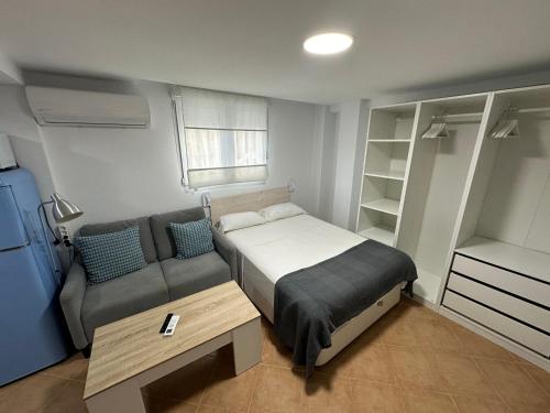 a small bedroom with a bed and a couch at Apartamento Avenida Velazquez Planta Baja in Málaga