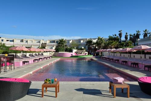 una piscina con sillas y sombrillas en un resort en Village Naturiste Cap d'Agde, 208 Résidence de luxe les Jardins d'Eden "Réservée aux couples", en Cap d'Agde