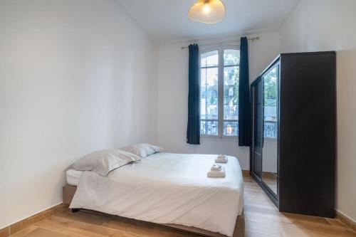 une chambre avec un lit blanc et une fenêtre dans l'établissement Appartement Métro Alexandre Dumas - II, à Paris