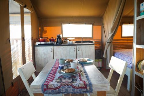 a table with a plate of food on it at Tendu' Punta Bianca Glamping Camp in Palma di Montechiaro