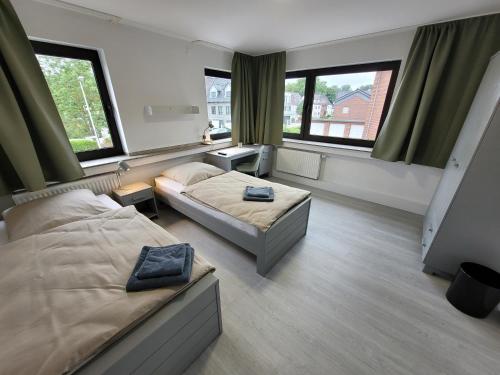 a bedroom with two beds and two windows at Guesthouse WI rooms in Jülich