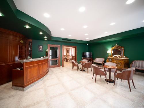 a living room with green walls and tables and chairs at Hotel SAN PIO in San Giovanni Rotondo