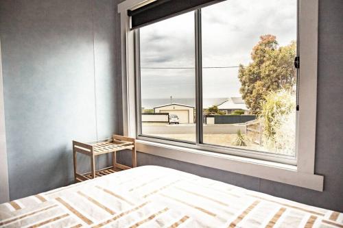 a bedroom with a bed and a large window at Wave Side Cottage Scamander Sleeps 5 in Scamander