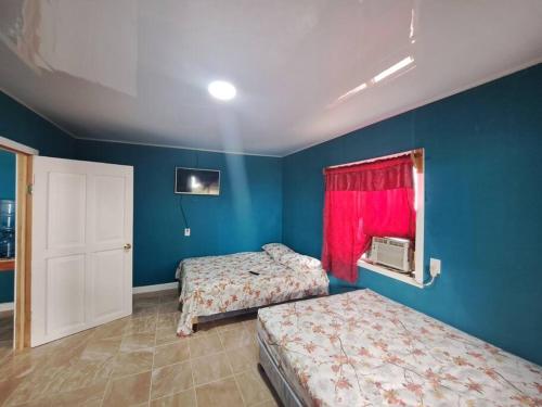 2 camas en una habitación con paredes azules y ventana en Apartamento La Estrella, en El Remate