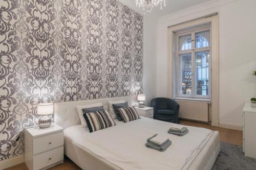 ブダペストにあるNagyDiofa Apartmentの白いベッドと壁が備わるベッドルーム1室が備わります。