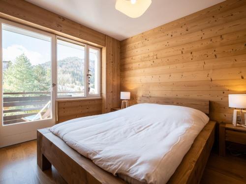- une chambre avec des murs en bois et un lit avec une fenêtre dans l'établissement Chaleureux appart 2 pièces près des pistes 4 pers 3*** - FR-1-304-272, à La Clusaz