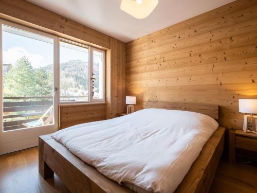 a bedroom with wooden walls and a bed with a window at Appartement La Clusaz, 2 pièces, 4 personnes - FR-1-304-272 in La Clusaz
