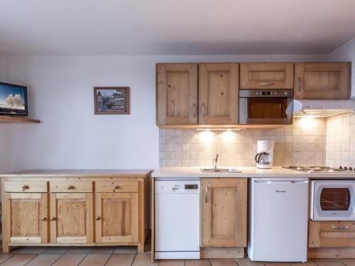 - une cuisine avec des placards en bois et des appareils blancs dans l'établissement Studio 26m² plein sud, proche pistes et commerces, La Clusaz, garage inclus - FR-1-304-81, à La Clusaz