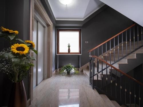 a hallway with a staircase with a window and flowers at Hotel SAN PIO in San Giovanni Rotondo