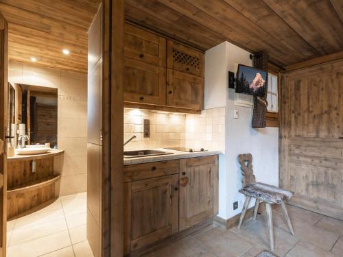 a kitchen with wooden cabinets and a sink and a chair at Chalet La Clusaz, 5 pièces, 8 personnes - FR-1-304-110 in La Clusaz