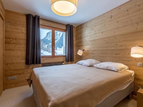 - une chambre dotée de murs en bois et d'un lit avec deux oreillers dans l'établissement 4 pièces près des pistes avec balcon - La Clusaz - FR-1-304-205, à La Clusaz