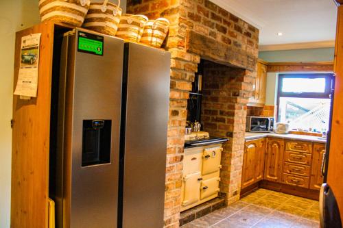 a kitchen with a stainless steel refrigerator and a brick wall at The Coach Inn in Strabane