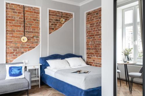 a bedroom with a blue bed and a brick wall at Apartments Factory in Sopot