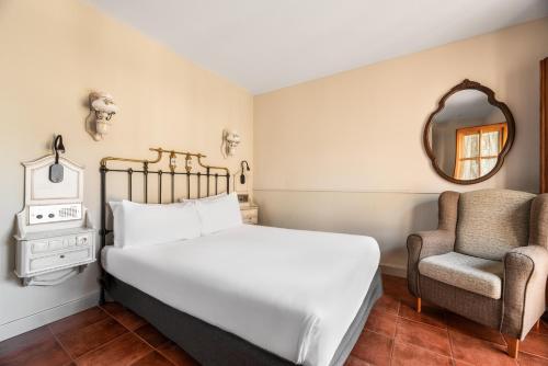 a bedroom with a bed and a chair at Crisol Mesón del Cid in Burgos