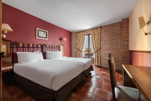 a large bed in a room with red walls at Crisol Mesón del Cid in Burgos