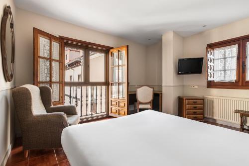 een slaapkamer met een bed en 2 stoelen en een televisie bij Crisol Mesón del Cid in Burgos