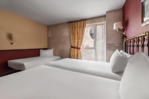 two beds in a room with a window at Crisol Mesón del Cid in Burgos