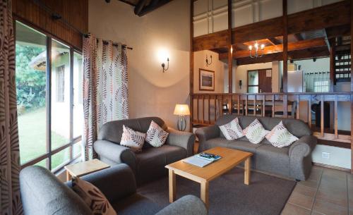- un salon avec deux canapés et une table dans l'établissement Fairways Drakensberg Resort, à Drakensberg Garden
