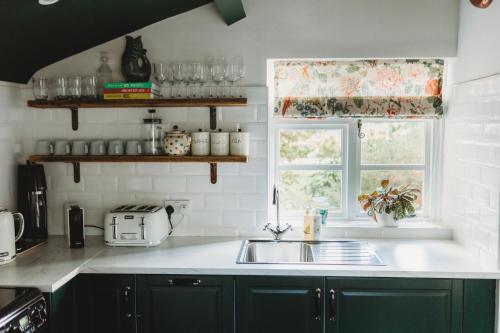 uma cozinha com armários verdes, um lavatório e uma janela em Luxury Cottage with Swimming Pool em Bredon