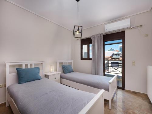 two beds in a room with a window at Galina's Greek House in Artemida