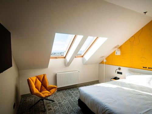 ein Schlafzimmer mit einem Bett, einem Fenster und einem Stuhl in der Unterkunft Ibis Styles Sibiu Arsenal in Sibiu