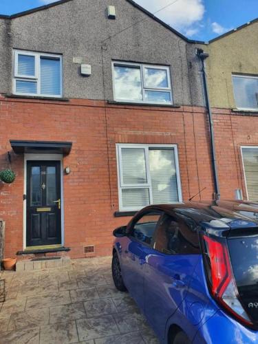 a blue car parked in front of a brick house at Single Bedroom 96GLA Greater Manchester in Middleton