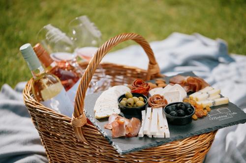 a picnic basket with food and wine on a blanket at Munkácsy Villa - Szekszárd in Szekszárd