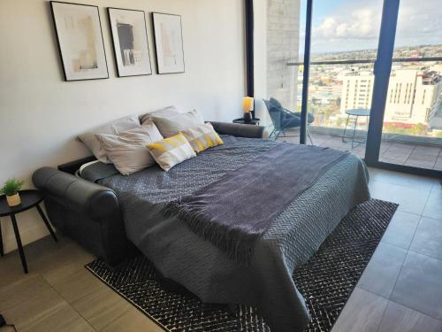 a large bed in a room with a large window at Downtown Apartment with Balcony City View, Gym & Lounge in Tijuana