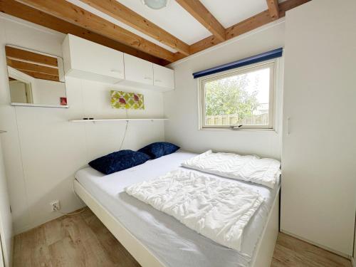 een slaapkamer met een bed in een kleine kamer bij Chalet 560 op Recreatiepark De Wielen in Sint Maarten