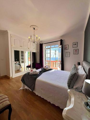 a bedroom with a large bed and a chandelier at Blue Paradise Apartment in Ribeira Brava