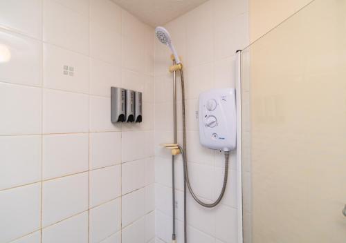 a shower in a bathroom with a blow dryer on the wall at Derby Mandarin 3 Bedroom Apartment with Garden and Parking in Derby