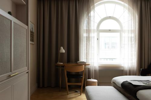 a bedroom with a bed and a desk in front of a window at Hotel St. George Helsinki in Helsinki