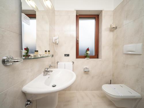 a white bathroom with a sink and a toilet at Hotel SAN PIO in San Giovanni Rotondo