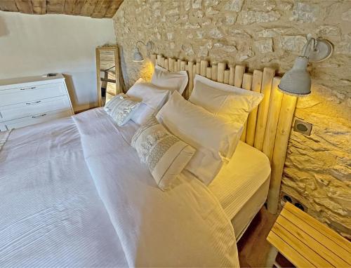 sypialnia z łóżkiem z białą pościelą i poduszkami w obiekcie La Bergerie de Foneri - Véritable mas en pierre pour 6 pers avec piscine chauffée w mieście Lorgues