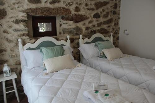 two beds in a room with a stone wall at Casa Paula in Segurilla