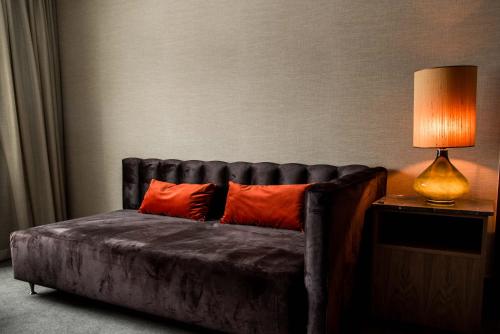 a leather couch with orange pillows next to a lamp at Billingehus in Skövde