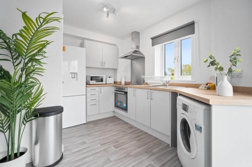 a white kitchen with a washing machine and a plant at Modern 2 Bedroom Apartment - Secure Parking - 53C in Sleightholme