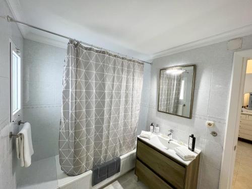ein Bad mit einer Dusche, einem Waschbecken und einem Spiegel in der Unterkunft Apartamento con vistas al mar a 1 min de la playa in Málaga