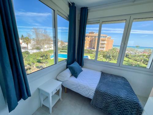 Schlafzimmer mit einem Bett und Fenstern mit Aussicht in der Unterkunft Apartamento con vistas al mar a 1 min de la playa in Málaga